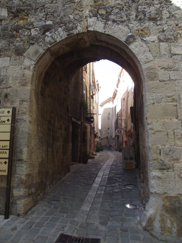 A stone archway reveals a small cobbled street.