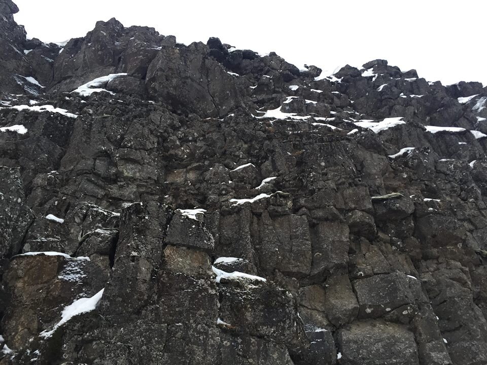 A wall of rock with scattered snow.