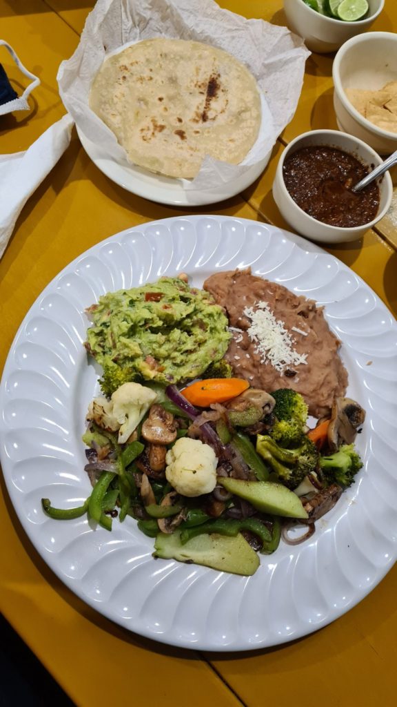 A plate piled high with vegetables, re-fried beans and guacamole.