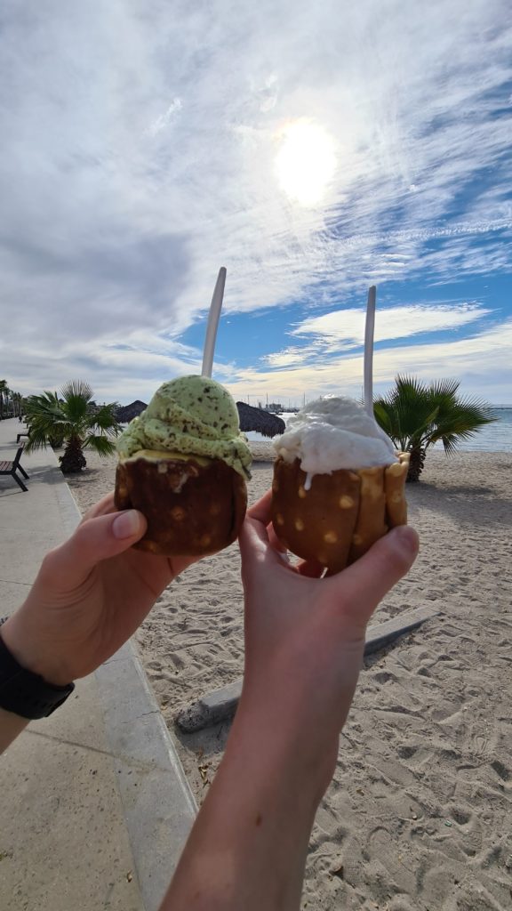 Two ice creams in bowls made from waffle-cones in front of the La Paz coastline.