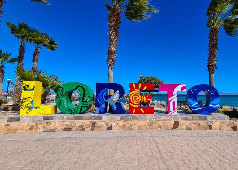 Neon coloured letters spell out "Loreto" on the seafront.