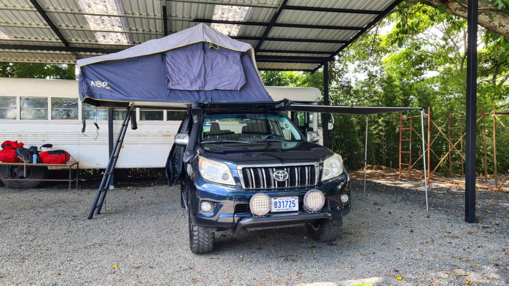 A camper car set up with tent and awning out.