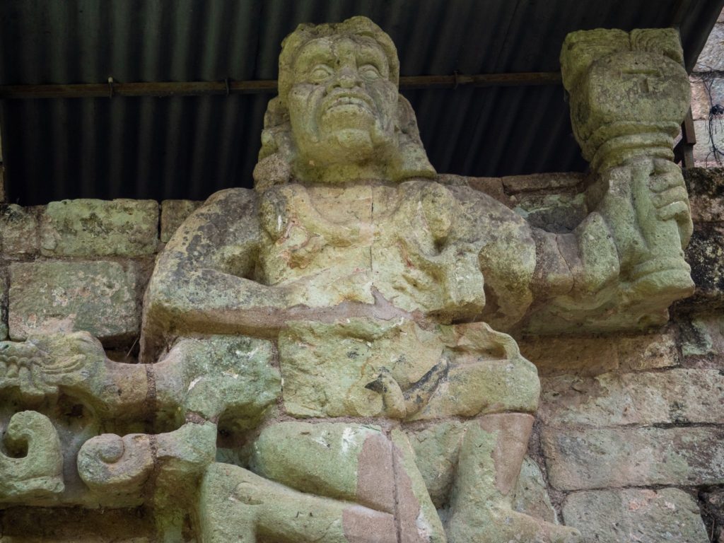 A kneeling figure, carved in stone, holds a torch.