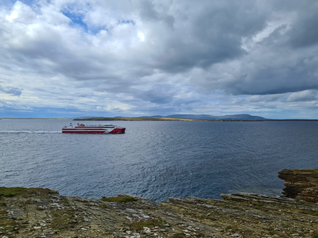 A red striped ferry makes its way from John O'Groats to St Margret's Hope.