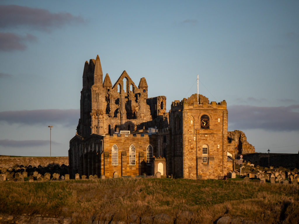 A golden light shines on Whitby Abbey at sunset.