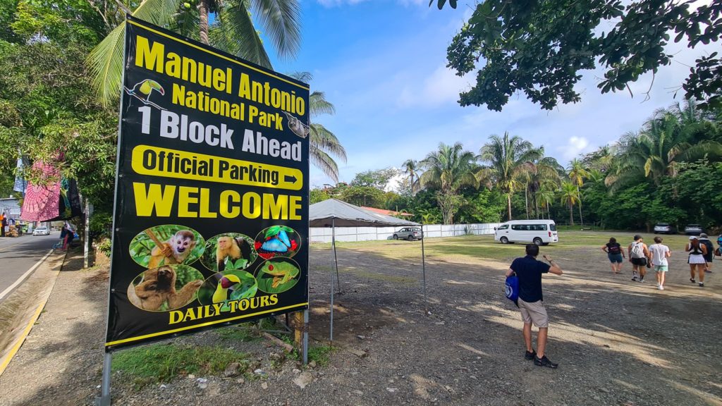 A large sign advertises parking for Manuel Antonio National Park.