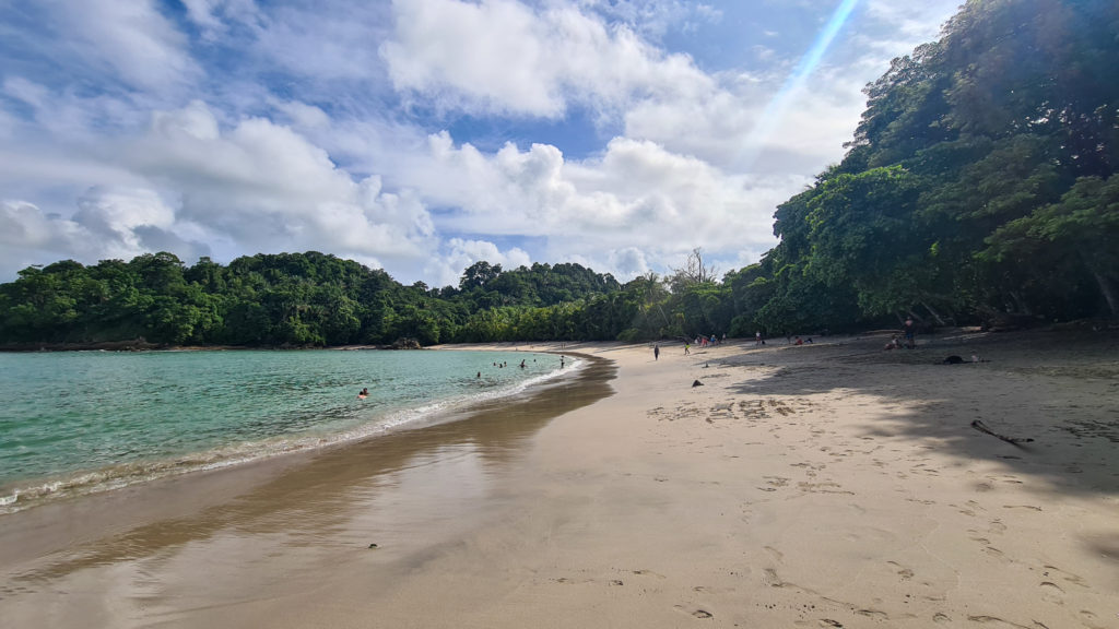 The coastline at Playa Manuel Antonio curves round in a wide arch of sand and greenery.