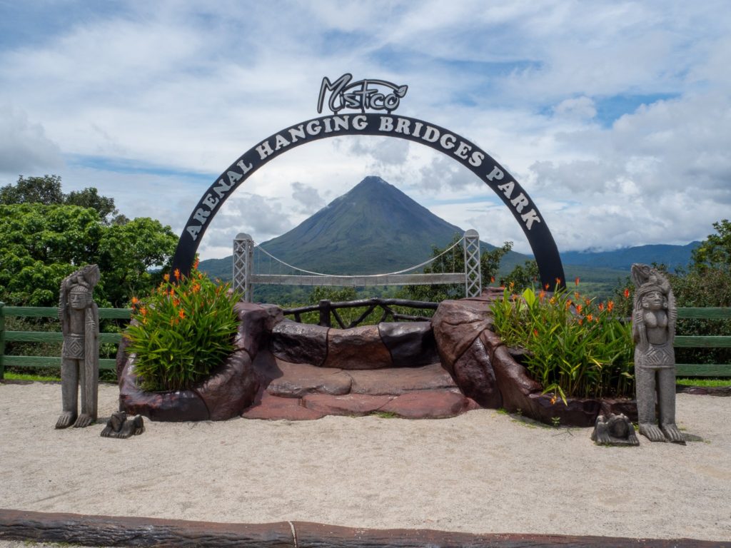 An archway frames Arenal Volcano, showing off its size in the sunshine.