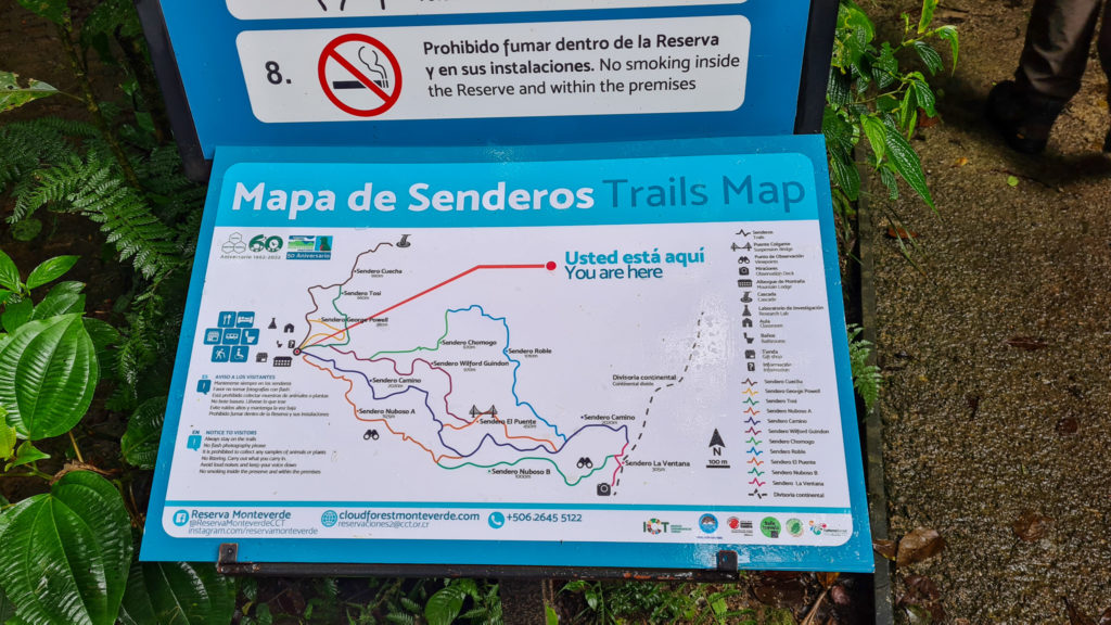 We see a map of all the hiking trails throughout the Monteverde cloud forest biological reserve. There is also a sign advising visitors that smoking is prohibited inside the Reserve.