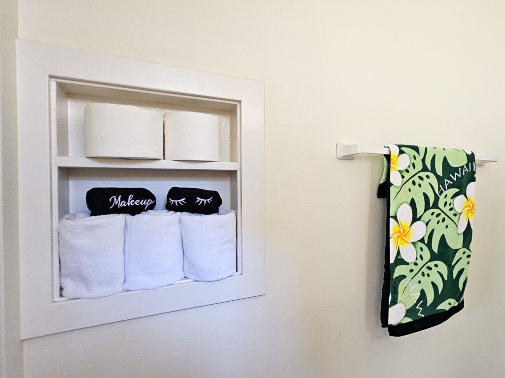 A group of towels arranged in a bathroom. One of the towels has the word "Hawaii" printed on it.