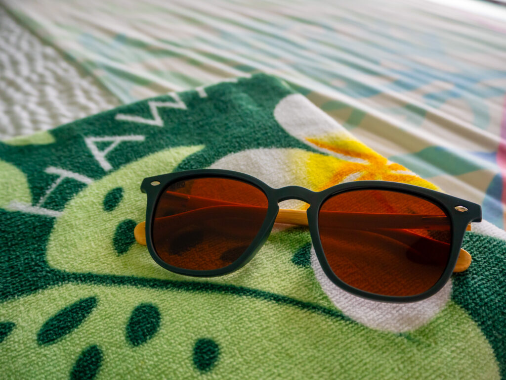 A close up view of a pair of sunglasses lying on a colourful towel.