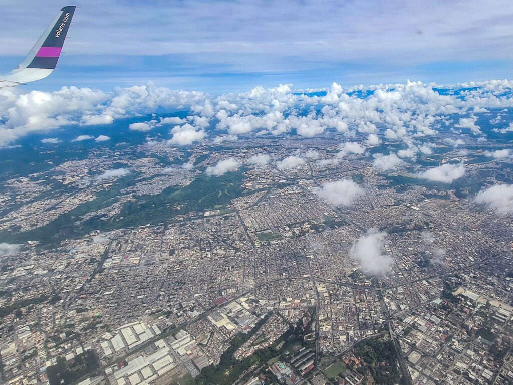 A vast city can be seen out of a plane window. Blocks of buildings seem to stretch on for miles.