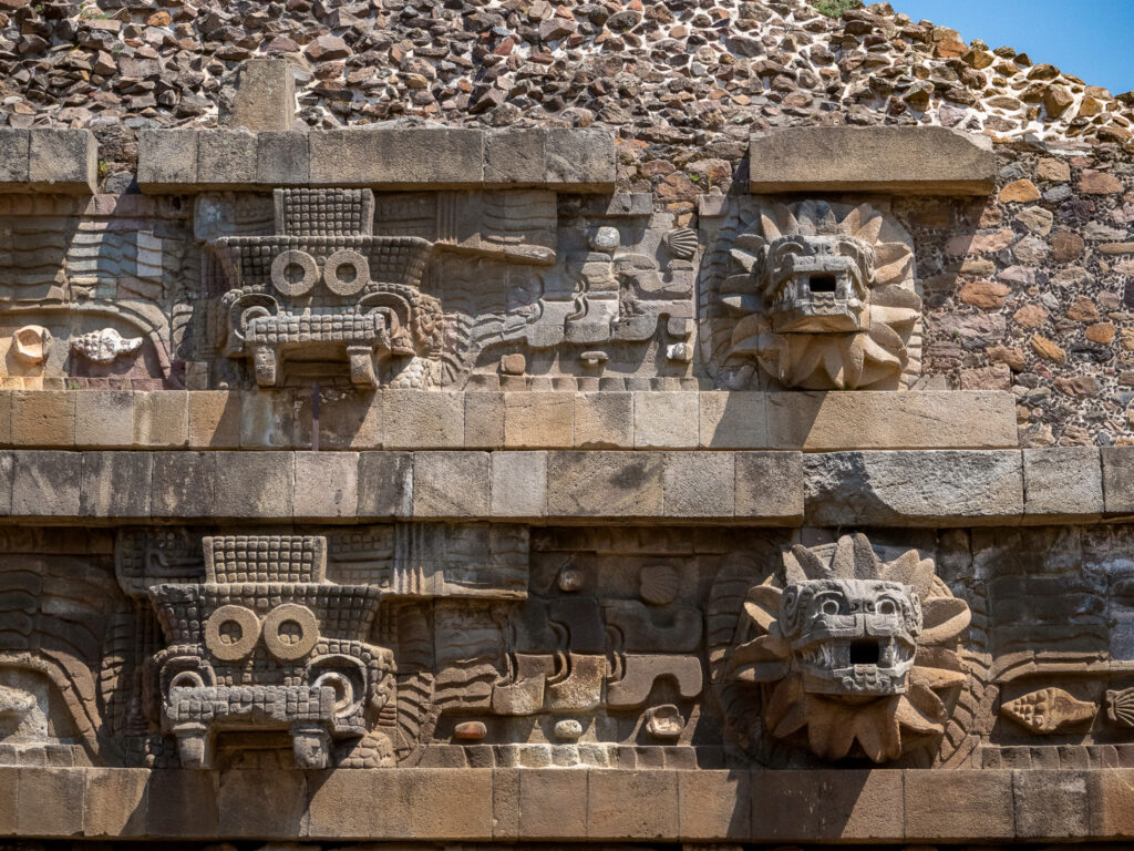 We see sculptures of the feathered serpent deity Quetzalcoatl on the side of a temple at Teotihuacan. These sculptures are carved in stone and the details are very impressive.