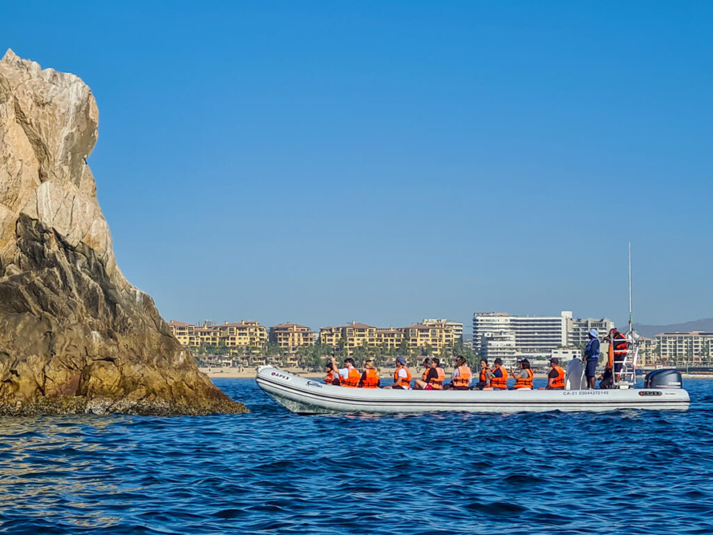 A small RIB lined with tourists in orange life vests stop to admire Cabo's rock formations.