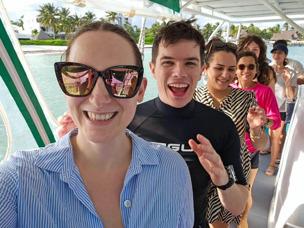 Dan and Lucy in a 'conga line' on a boat with Ocean Tours. Everyone is smiling and having fun.