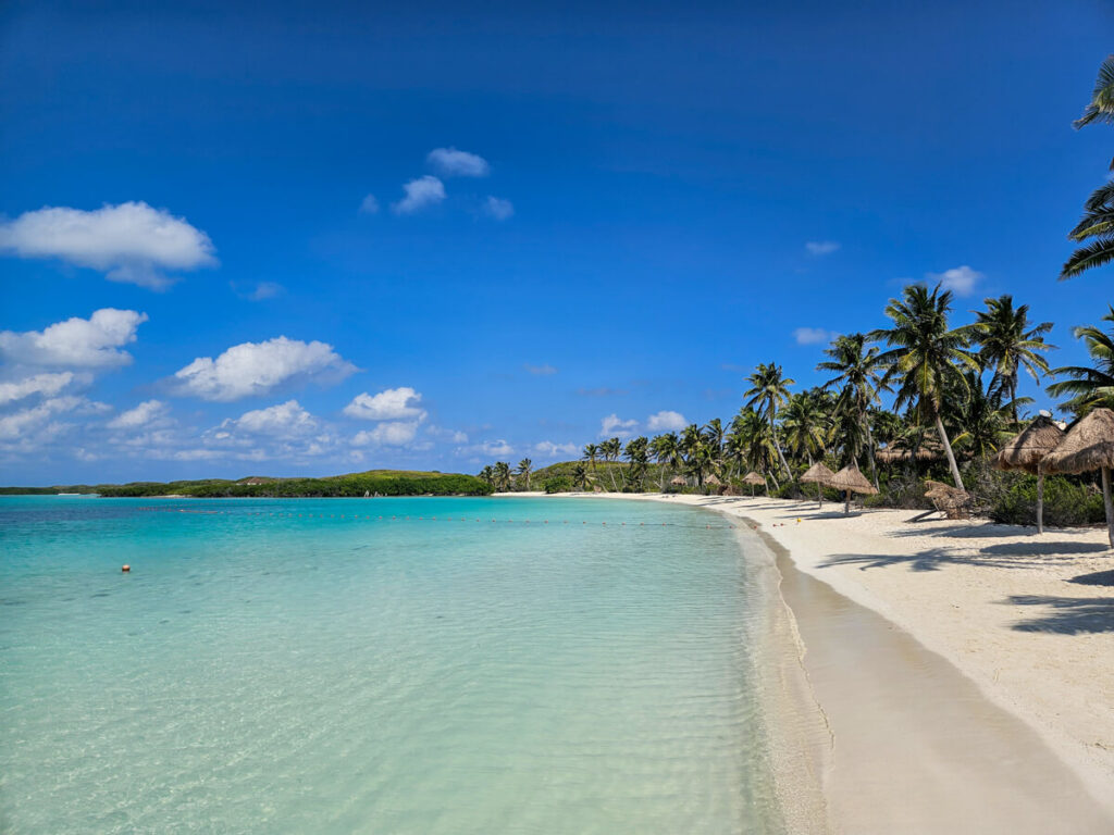 A completely empty beach on Isla Contoy. The sky is a clear blue and the water is light and calm.