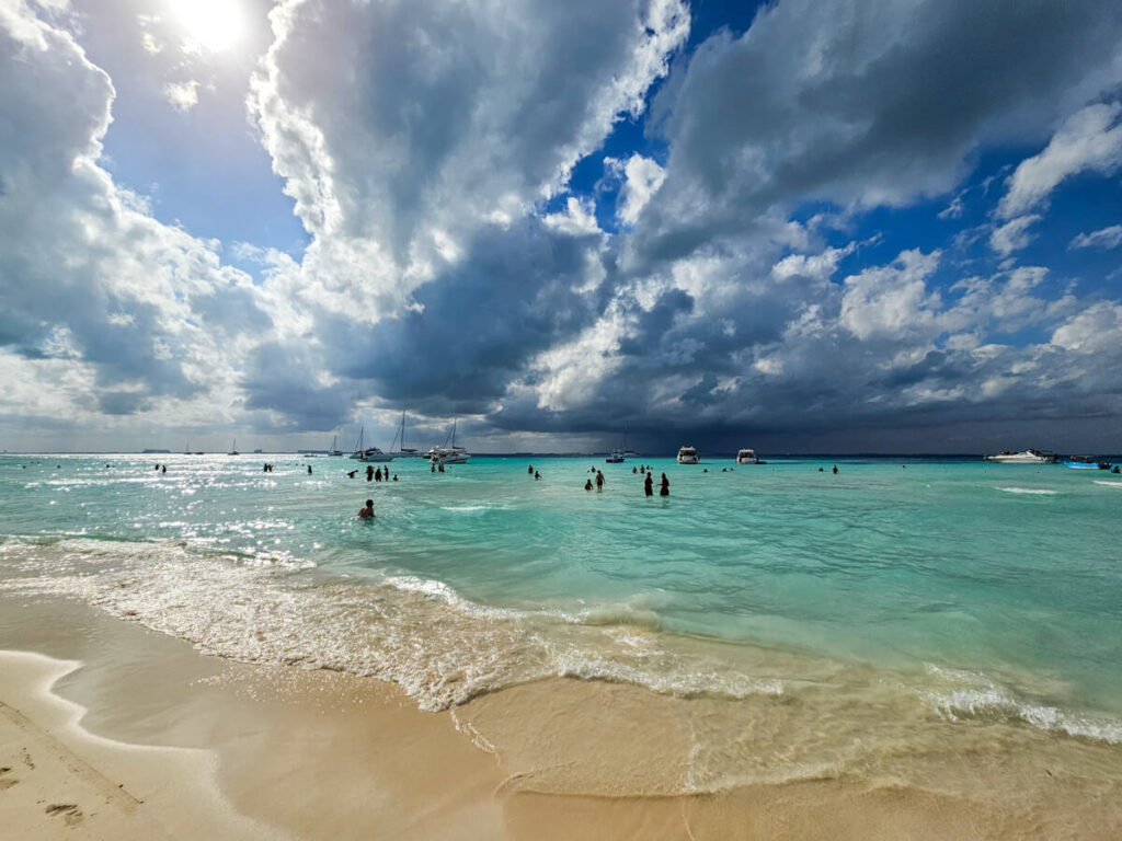 One of the best beaches in the world - Playa Norte on Isla Mujeres. The sky is moody and the sea is a milky blue colour.