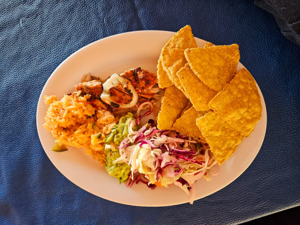 A plate of local Mexican food consisting of totopos, coleslaw, Tikin Xic, rice and guacemole.